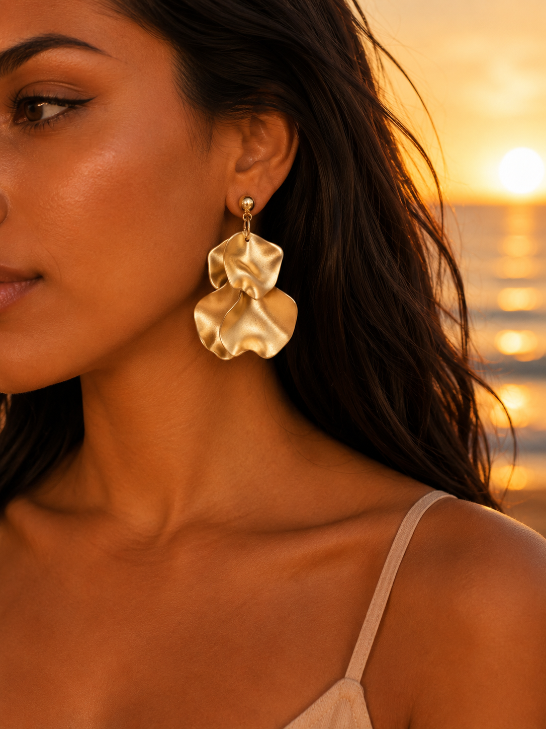 Boucles d'oreilles dorées Ondine de Bricotte & Co portées par une femme au coucher du soleil
